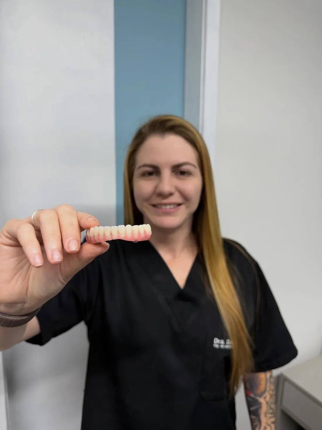 Dra. Daiane Cristo segurando uma prótese fixa no consultório da Full Saúde Integrada